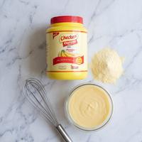 Checkers Milk Custard 1kg flat lay with whisk and prepared custard